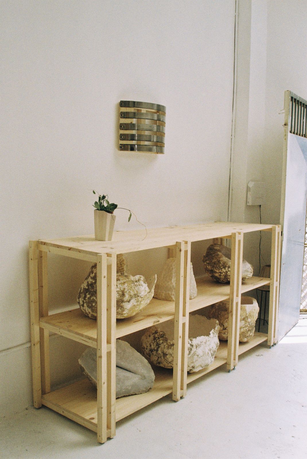 Wooden shelf with natural stones in the VORA HOUSE workshop